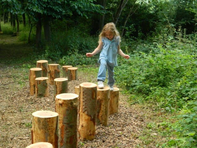 Hop across logs in the natural play area at Croft Castle, Herefordshire